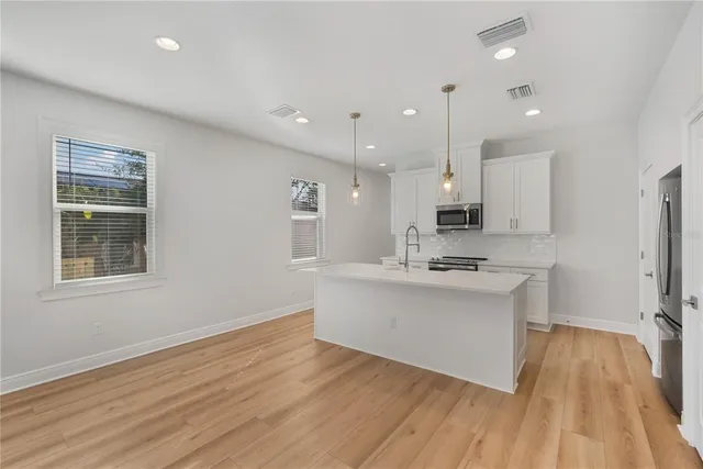 a large white kitchen with wooden floor and a window