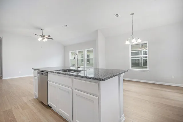 a kitchen with granite countertop a stove a sink and dishwasher with wooden floor
