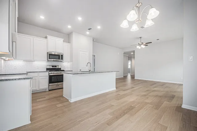 a large kitchen with cabinets wooden floor and stainless steel appliances