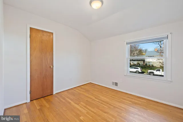 a view of an empty room with window and wooden floor