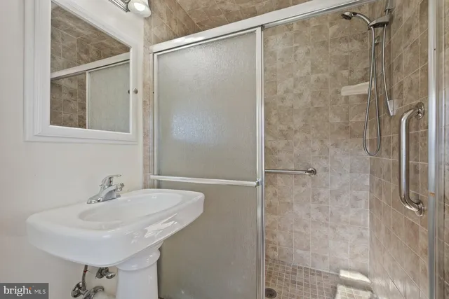 a bathroom with a sink shower and a mirror