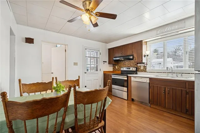 a kitchen with stainless steel appliances granite countertop a stove a sink dishwasher a dining table and chairs with wooden floor