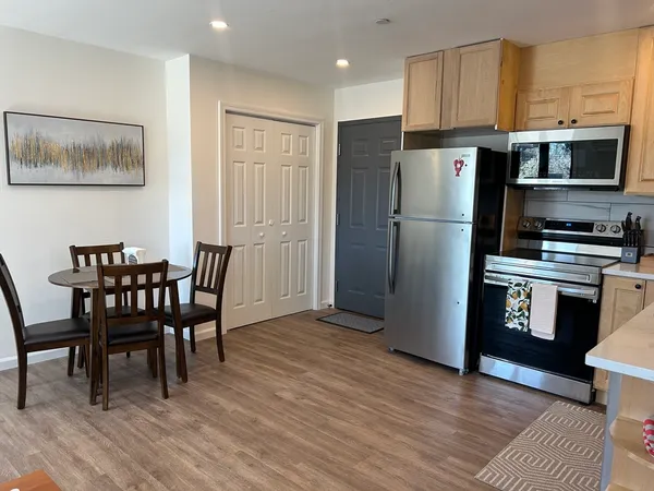 a kitchen with stainless steel appliances a refrigerator a stove a dining table and chairs