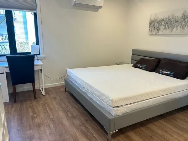 a bedroom with a bed and a chair with the wooden floor