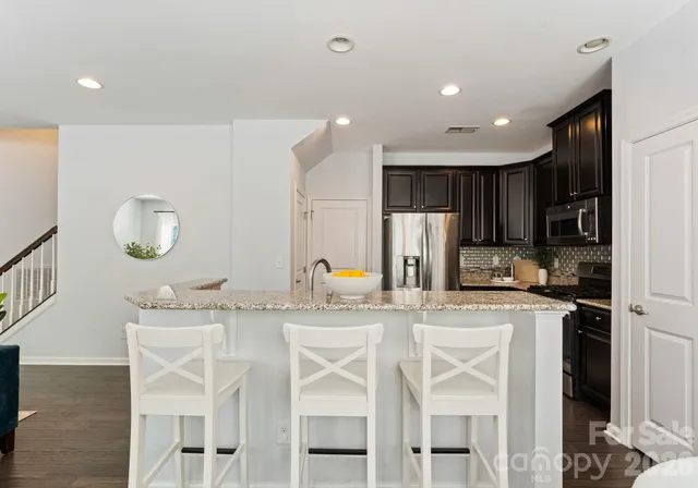 a kitchen with stainless steel appliances kitchen island granite countertop a stove a table and chairs