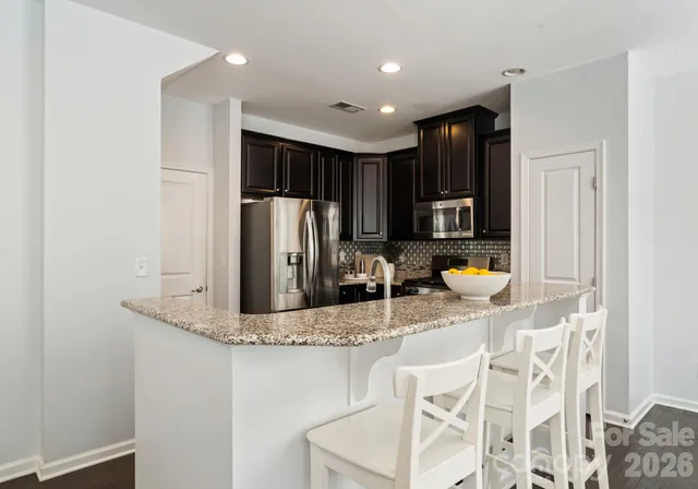 a kitchen with stainless steel appliances granite countertop a refrigerator a stove and a refrigerator with wooden floor