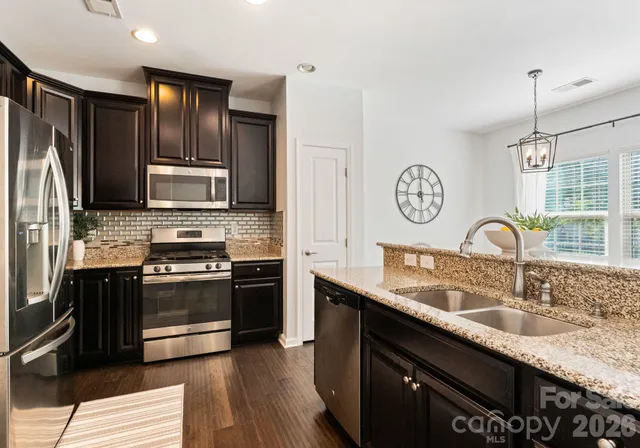 a kitchen with stainless steel appliances granite countertop a sink stove top oven and refrigerator