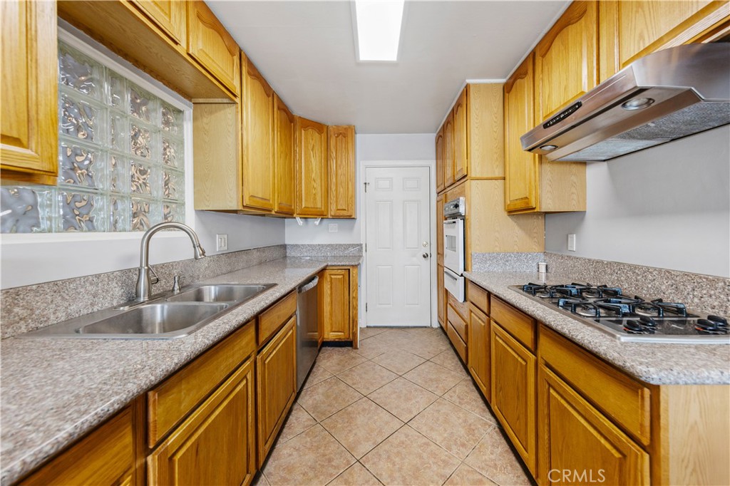 461 West Blaine Street Riverside, CA 92507 - Photo 7 of 22 a kitchen with sink a stove and a wooden cabinets