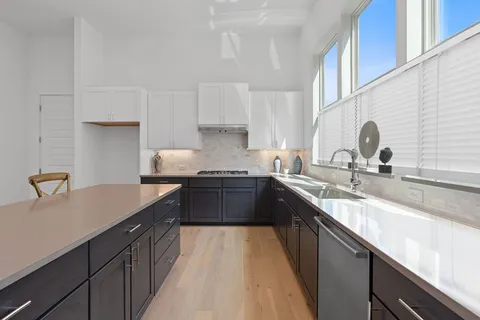 a kitchen with a sink dishwasher a stove top oven a refrigerator and cabinets