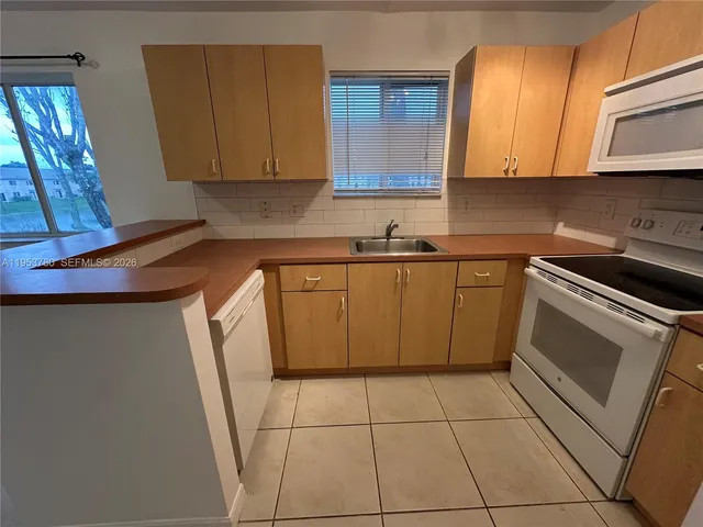 a kitchen with a sink a stove top oven and cabinetry