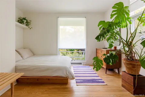 a bedroom with a bed table and a potted plant