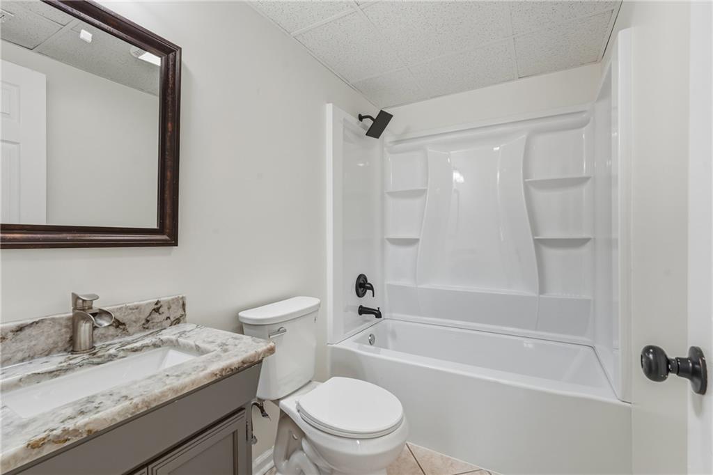 615 Amberwood Place Euharlee, GA 30145 - Photo 30 of 37 a bathroom with a granite countertop toilet a sink and a bathtub
