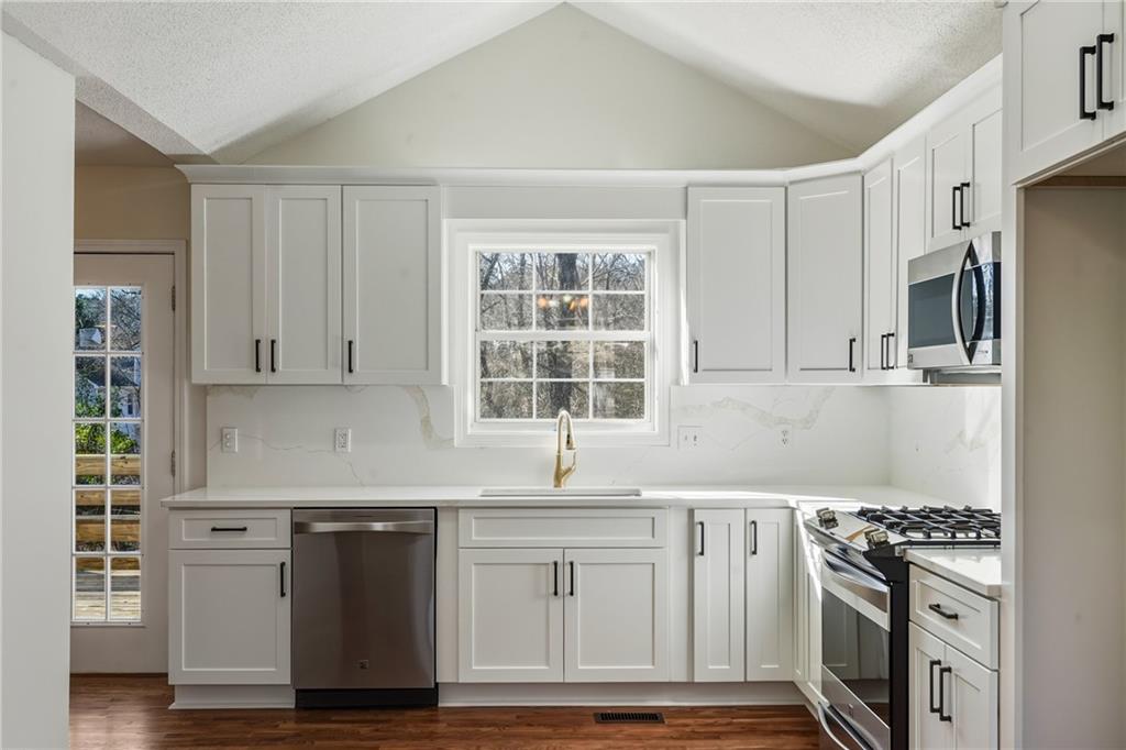 615 Amberwood Place Euharlee, GA 30145 - Photo 6 of 37 a kitchen with granite countertop a sink cabinets stainless steel appliances and a window