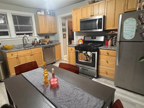 a kitchen with stainless steel appliances granite countertop a sink dishwasher stove and microwave with wooden floor