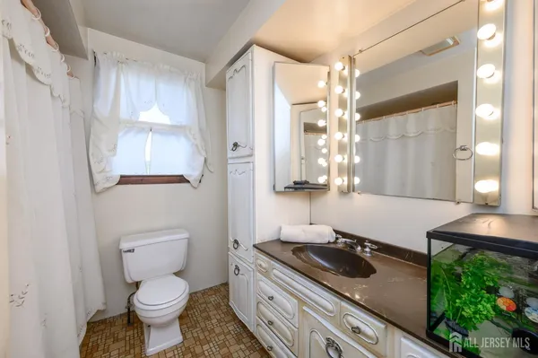 a bathroom with a granite countertop toilet sink and mirror