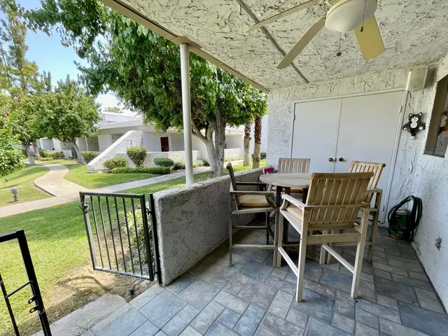 a view of a patio with table and chairs with wooden floor and fence