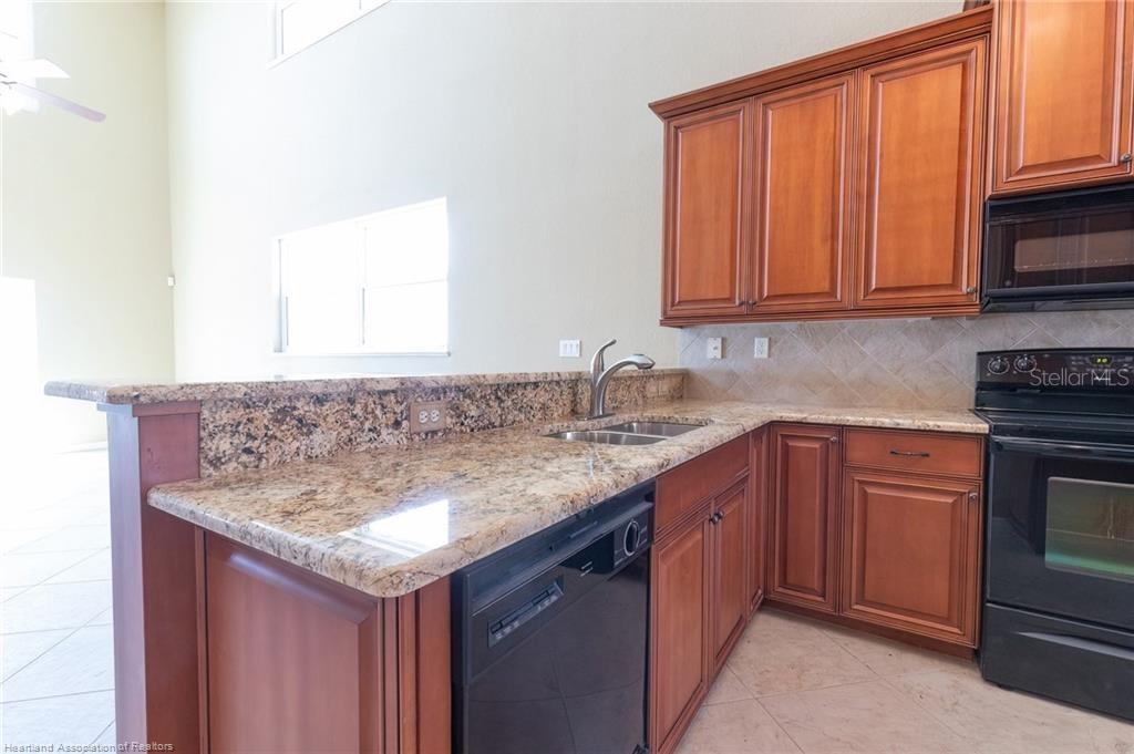 1900 Oasis Boulevard Sebring, FL 33870 - Photo 15 of 18 a kitchen with granite countertop a sink stove and cabinets