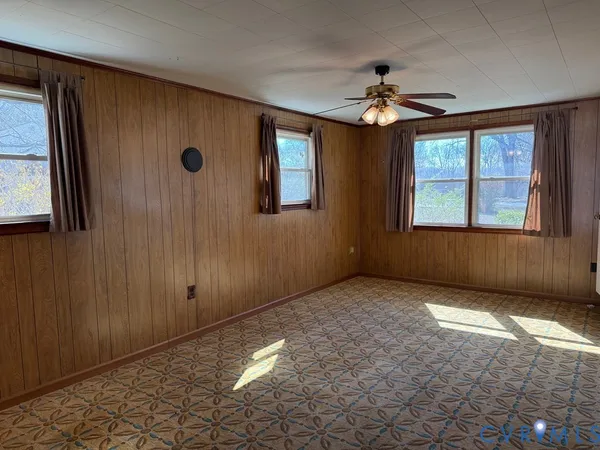 an empty room with windows and chandelier fan