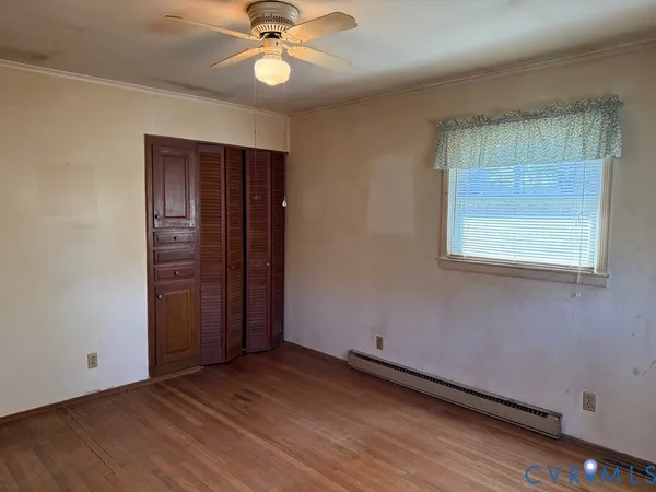 an empty room with wooden floor closet and windows
