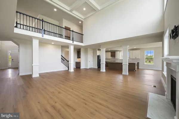 a view of empty room with wooden floor and a kitchen