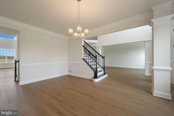 a view of an empty room with wooden floor and a chandelier