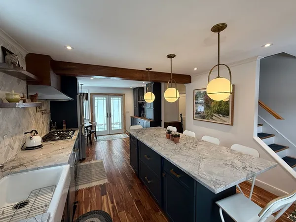 a dining hall with stainless steel appliances granite countertop a stove a sink dishwasher and a flat screen tv with kitchen view