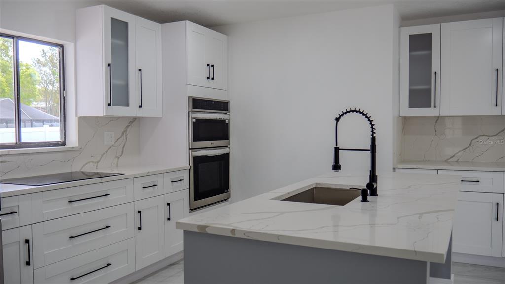 7984 Floral Drive Weeki Wachee, FL 34607 - Photo 7 of 31 a kitchen with granite countertop white cabinets and appliances