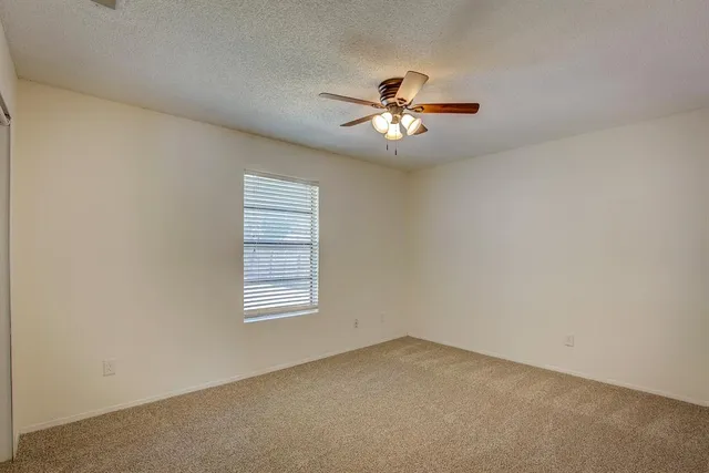 an empty room with windows and ceiling fan