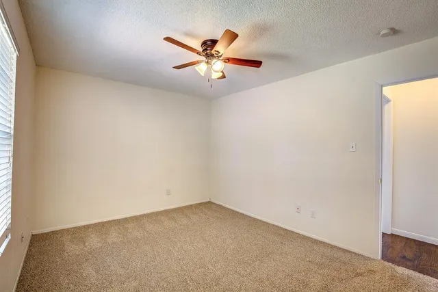 an empty room with a window and a ceiling fan