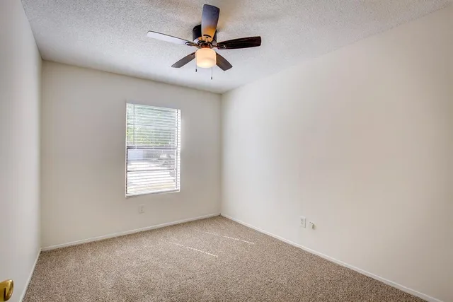 an empty room with a window and a fan