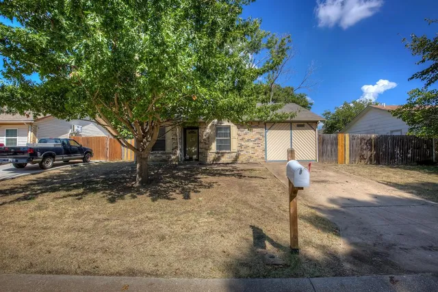 a front view of a house with a yard and a tree