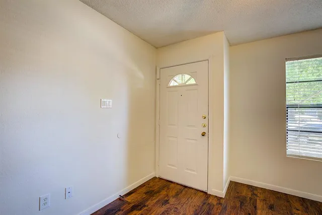 an empty room with wooden floor and window