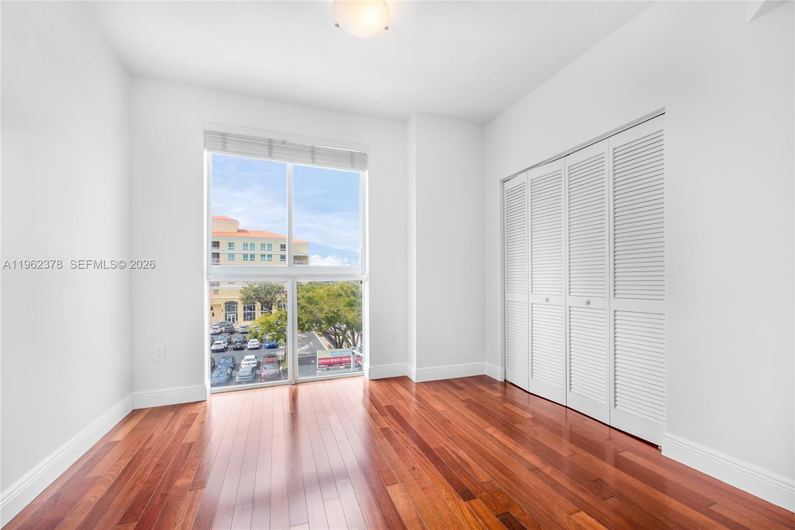 7270 Southwest 88th Street, Unit B303 Miami, FL 33156 - Photo 9 of 15 an empty room with wooden floor and windows