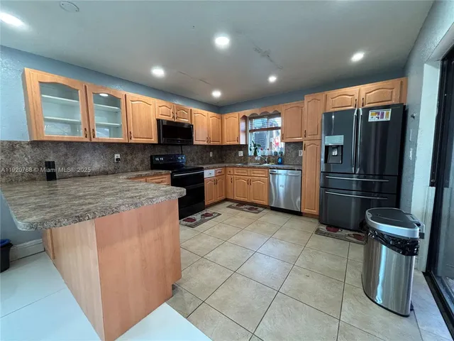 a kitchen with stainless steel appliances granite countertop a sink stove refrigerator and cabinets