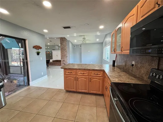 a large kitchen with stainless steel appliances granite countertop a large stove a sink and a microwave