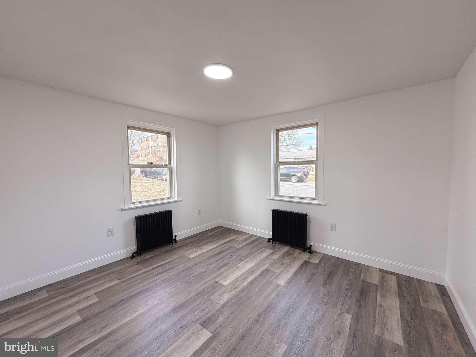 1424 Wayne Street Reading, PA 19601 - Photo 6 of 19 an empty room with wooden floor a window and a fireplace