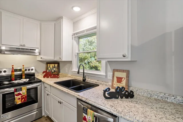 a kitchen with granite countertop a sink a stove and cabinets