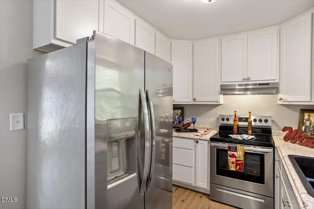 a kitchen with stainless steel appliances granite countertop a refrigerator and a stove top oven