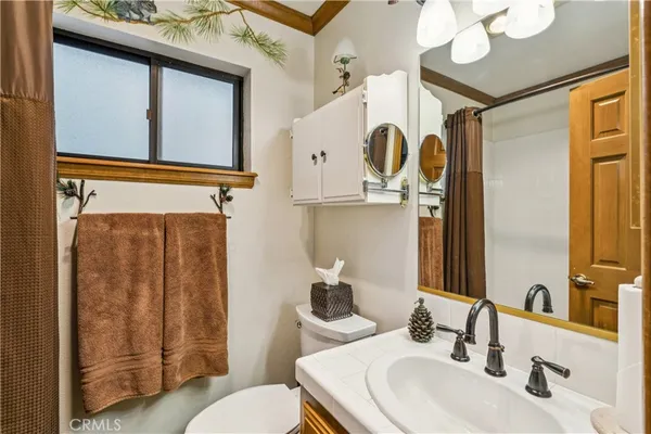 a bathroom with a sink a toilet mirror and shower