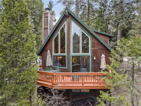 a view of small house with wooden deck and furniture