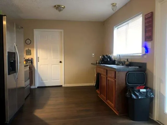 a kitchen with granite countertop a refrigerator a sink dishwasher stove and wooden cabinets