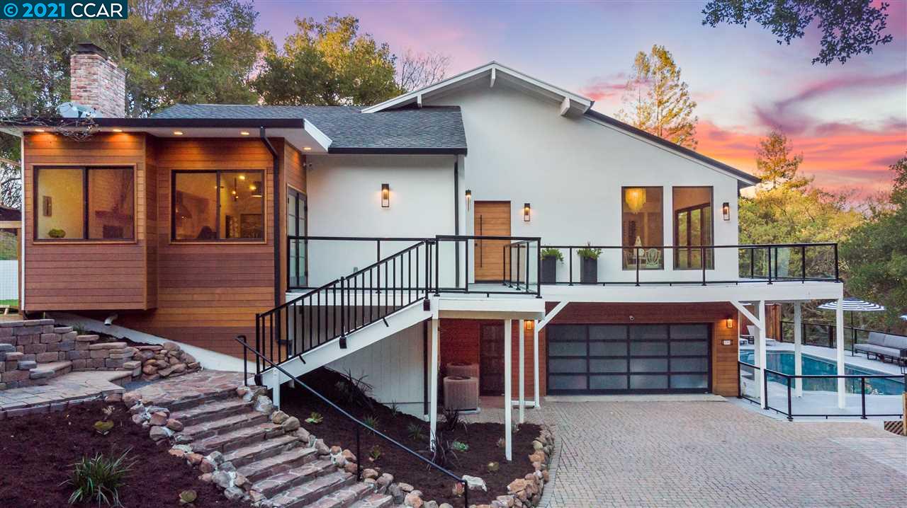 a view of front of house with wooden deck and furniture