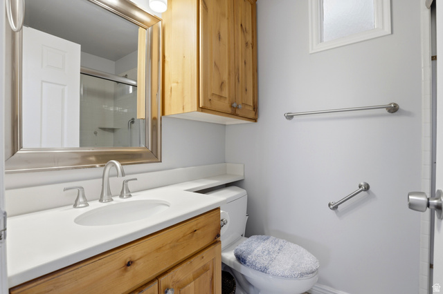 4245 3320 East Holladay, UT 84124 - Photo 27 of 51 Bathroom featuring a wood-finish vanity with a white countertop and integrated sink, a framed mirror, and an overhead wood-finish cabinet