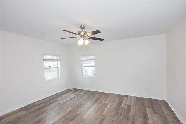 an empty room with wooden floor window and ceiling fan