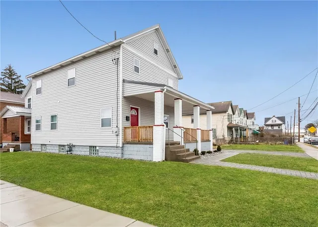 a view of a white house with a big yard and sitting area