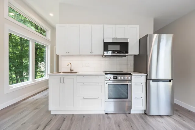 a kitchen with cabinets stainless steel appliances a sink and a window