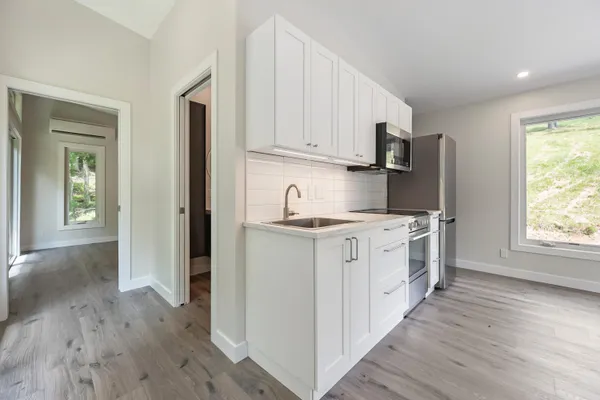 a kitchen with white cabinets and wooden floor