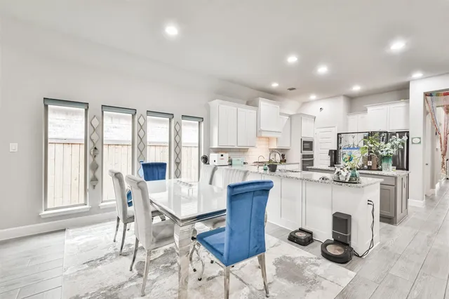 a kitchen with a dining table chairs and refrigerator