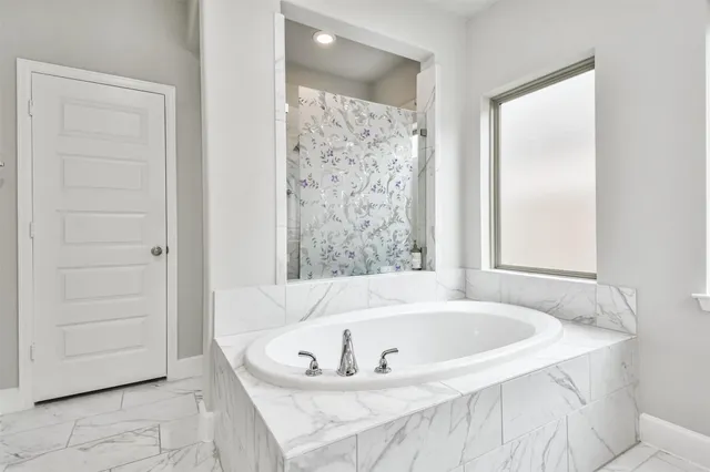 a white bath tub sitting in a bathroom near a bathroom