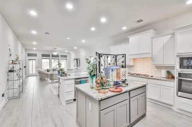 a kitchen with a sink dishwasher stove and white cabinets with wooden floor